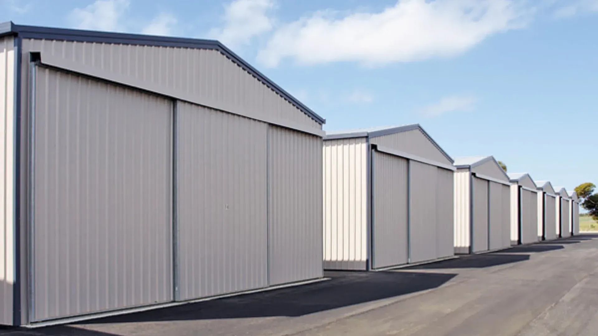 A Row of White Buildings With Sliding Doors — Hastings Valley Sheds in Laurieton, NSW