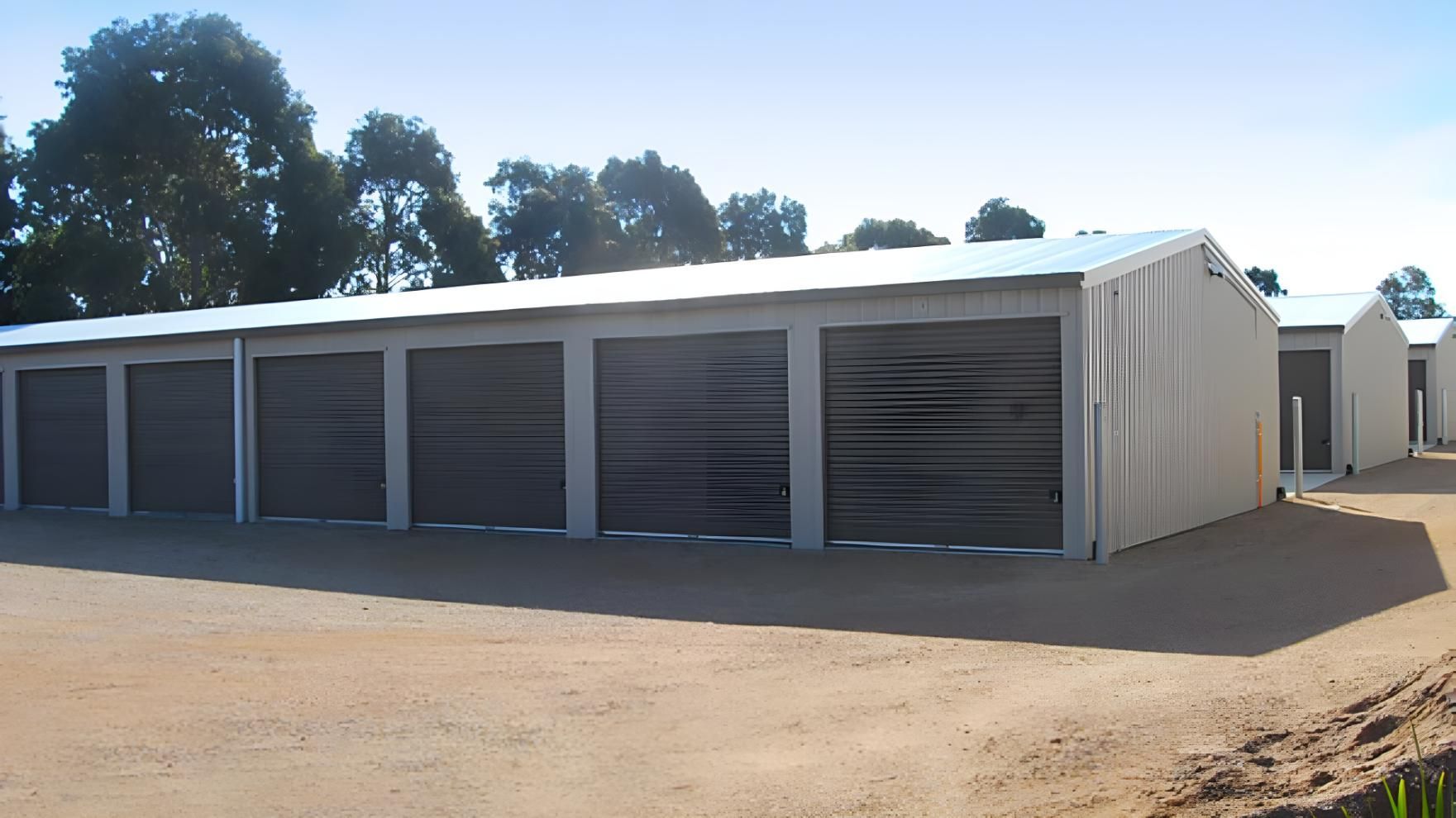A Row of Garage Doors Are Lined Up on a Dirt Road — Hastings Valley Sheds in Kempsey, NSW