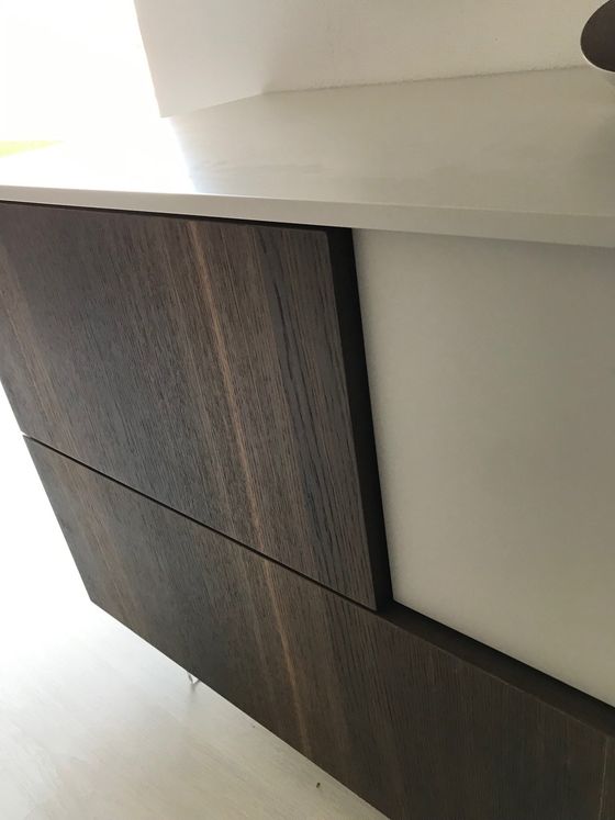Boiserie in legno scuro sul mobile con piano di lavoro bianco.