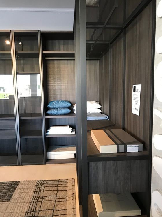 Scaffali in legno scuro integrati e nicchia con cuscini, libri e un tappeto.