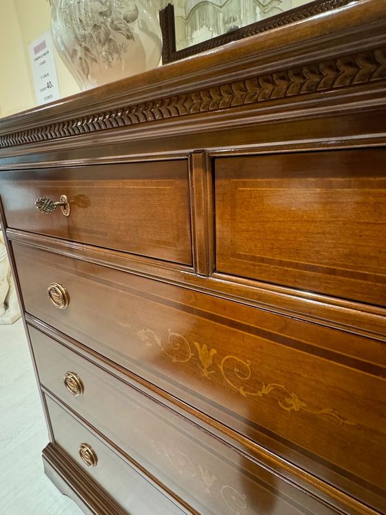 Cassettiera in legno con intagli elaborati, dotata di cassetti e ferramenta decorativa.