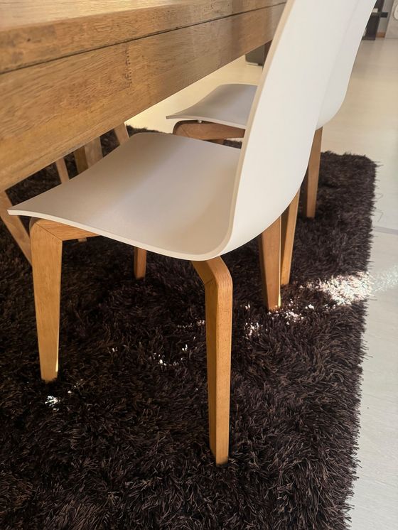 Sedia bianca con gambe in legno su un tavolo, su un tappeto scuro.