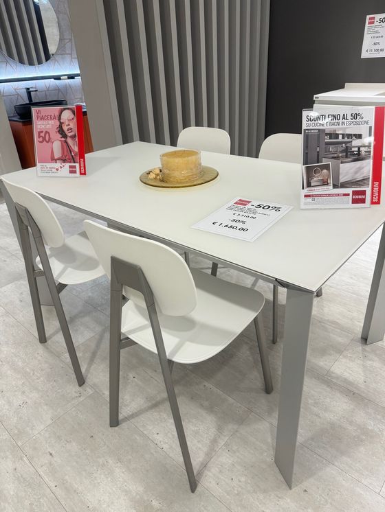 Tavolo da pranzo bianco con quattro sedie abbinate in uno showroom.
