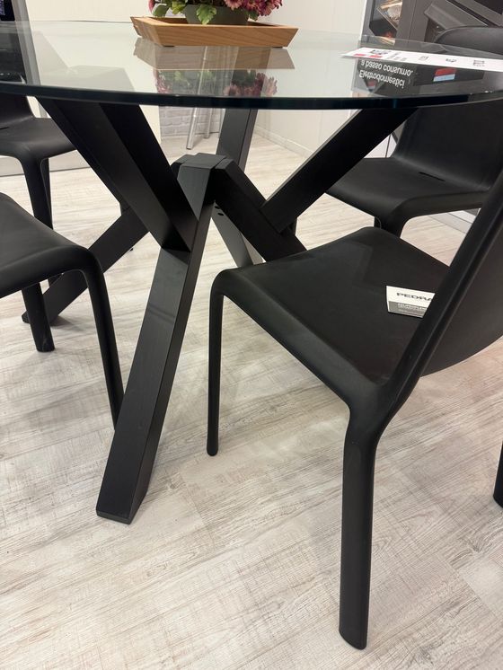 Tavolo nero con piano in vetro e sedie abbinate su tappeto a fantasia.