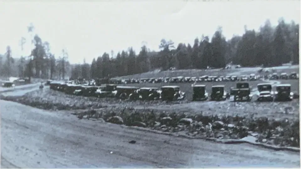 A black and white photo of cars parked on the side of the road