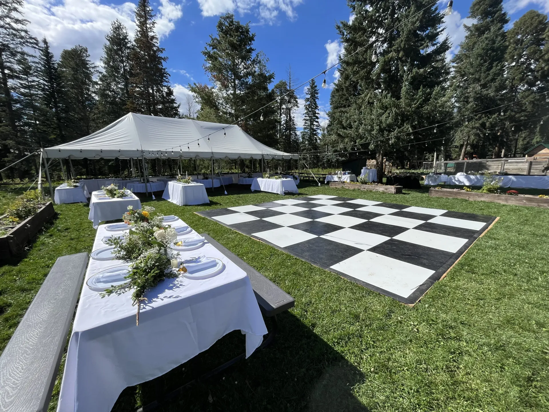 There is a large checkered dance floor in the middle of the grass.