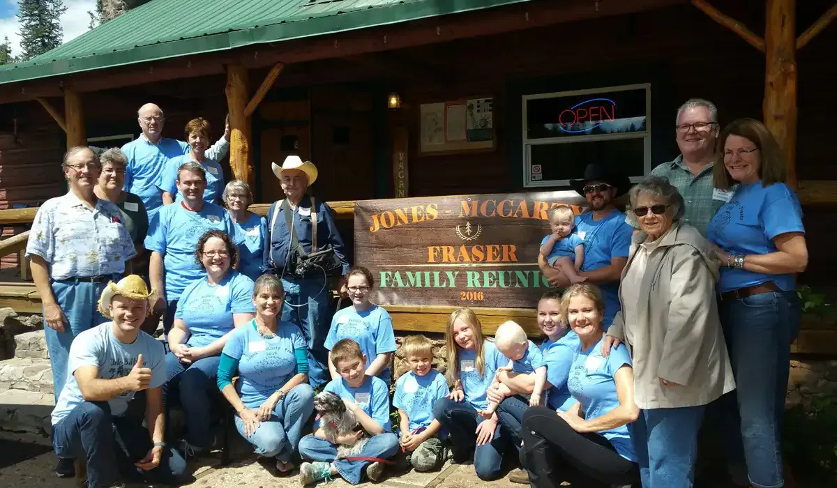 A group of people posing for a picture in front of a log cabin