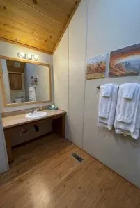 A bathroom with a sink , mirror and towels hanging on the wall.