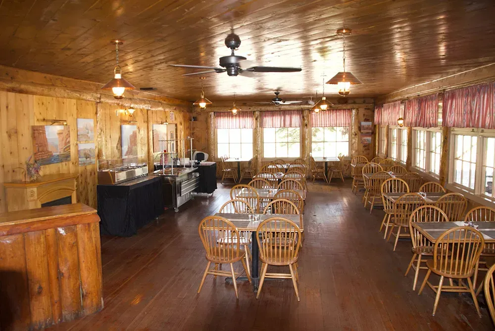 A restaurant with tables and chairs and a ceiling fan