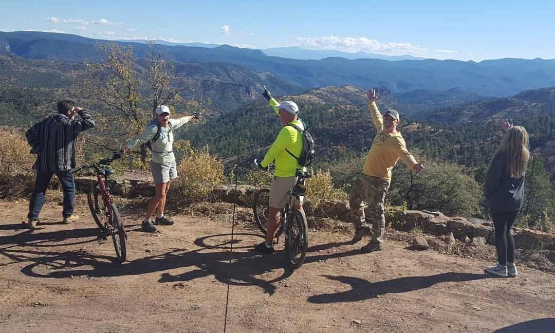A group of people standing on top of a dirt hill with bicycles.