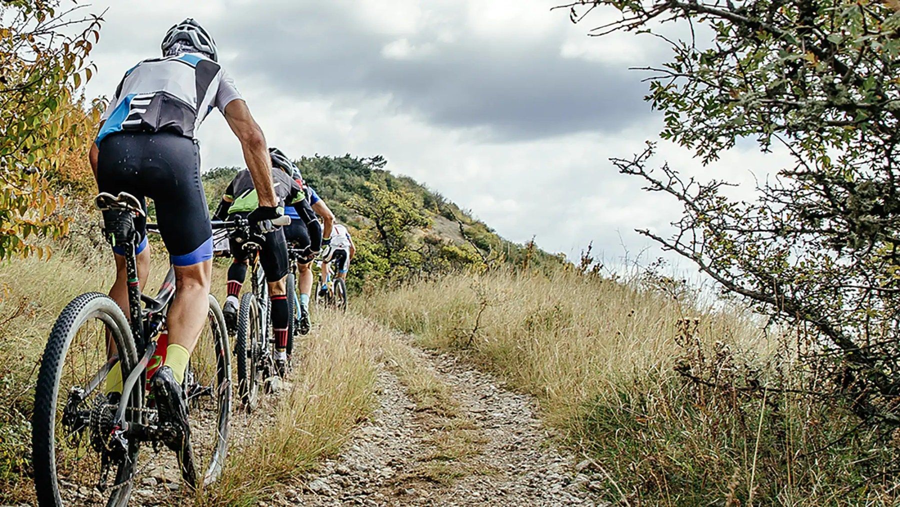 A group of people are riding bicycles down a dirt road.
