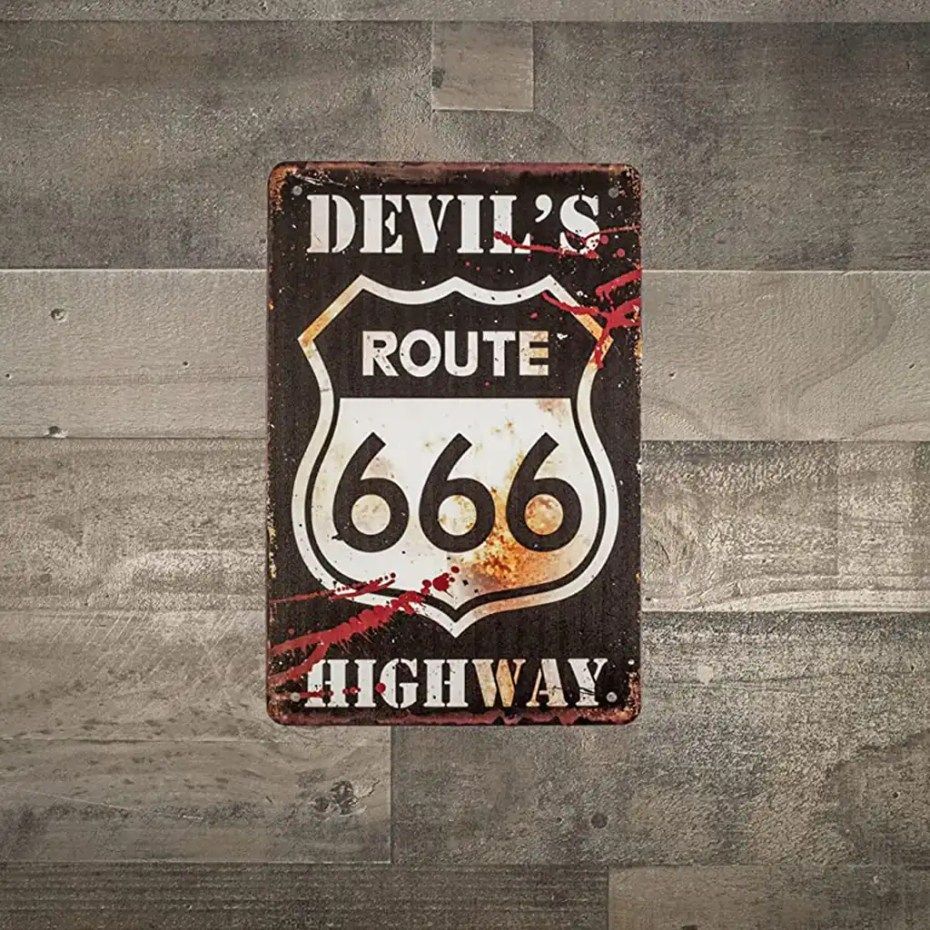 A devil 's route 666 highway sign is hanging on a wooden wall.