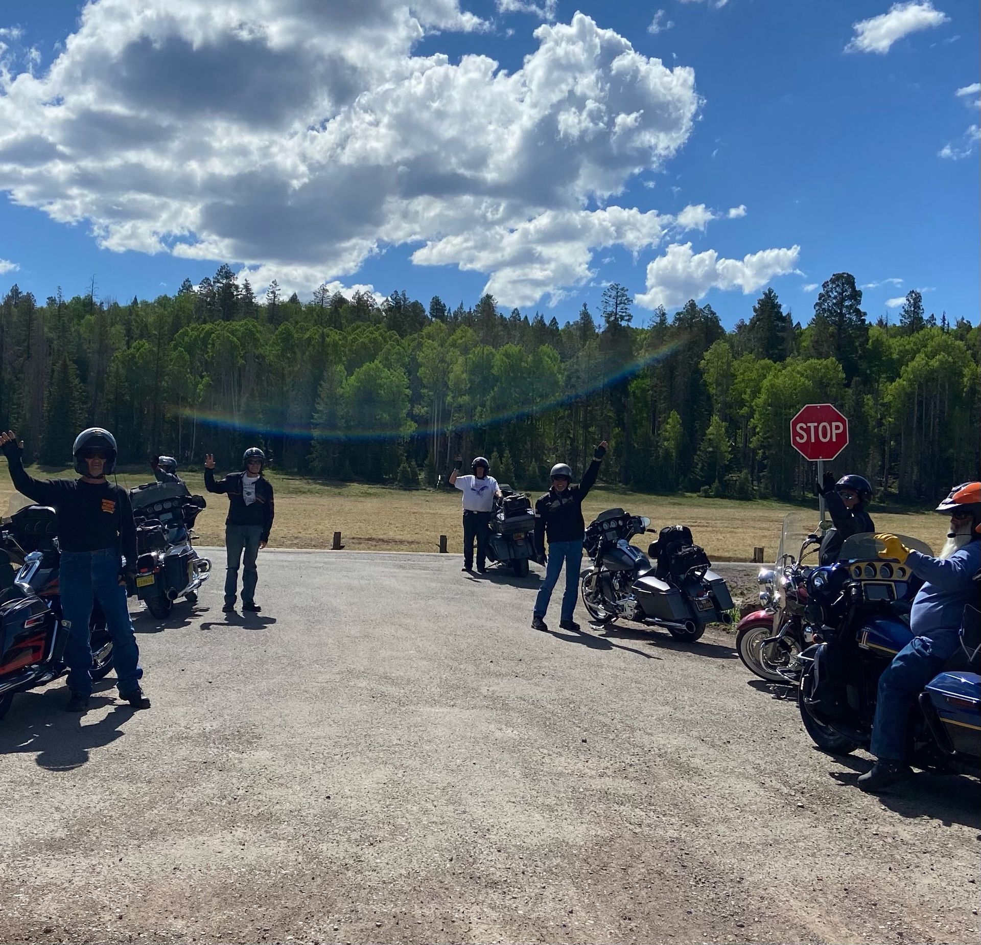 A group of motorcycle riders are standing in front of a stop sign