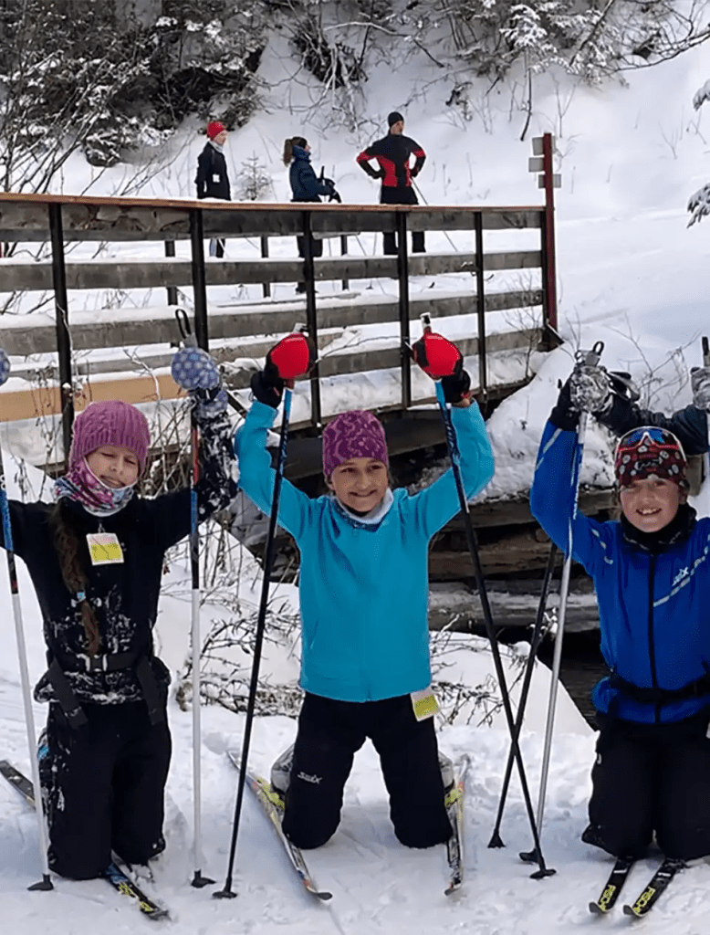Three people are posing for a picture while skiing in the snow
