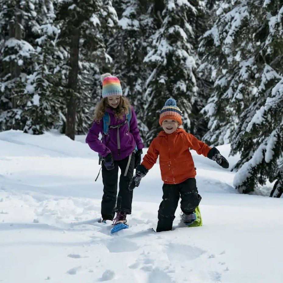 A boy and a girl are snowshoeing in the snow
