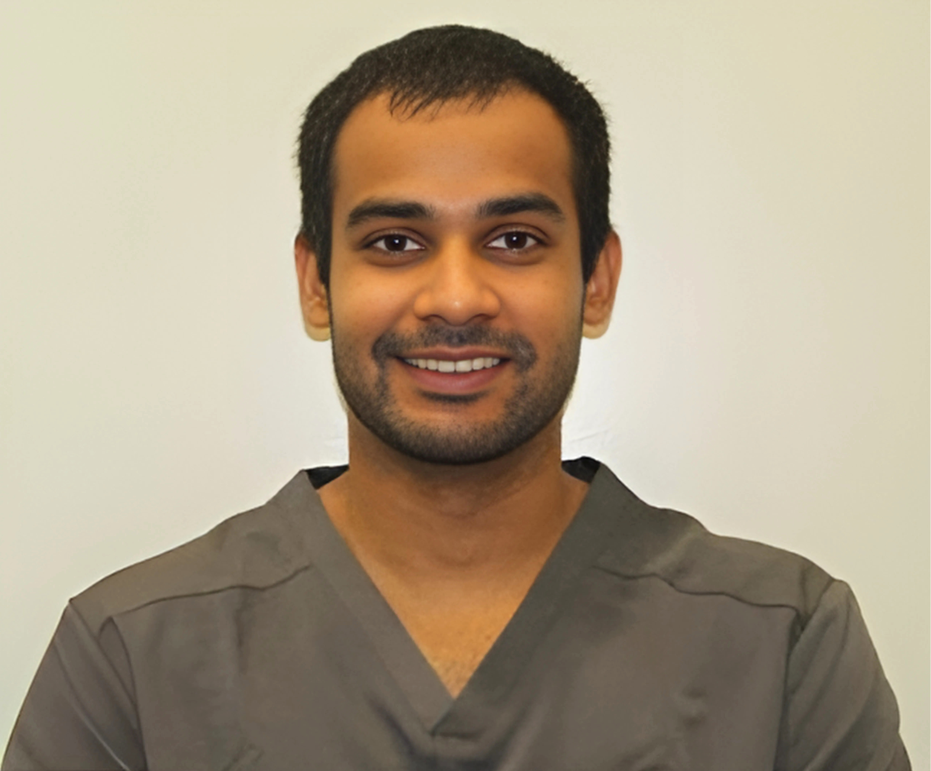 A man in a scrub top is smiling for the camera.