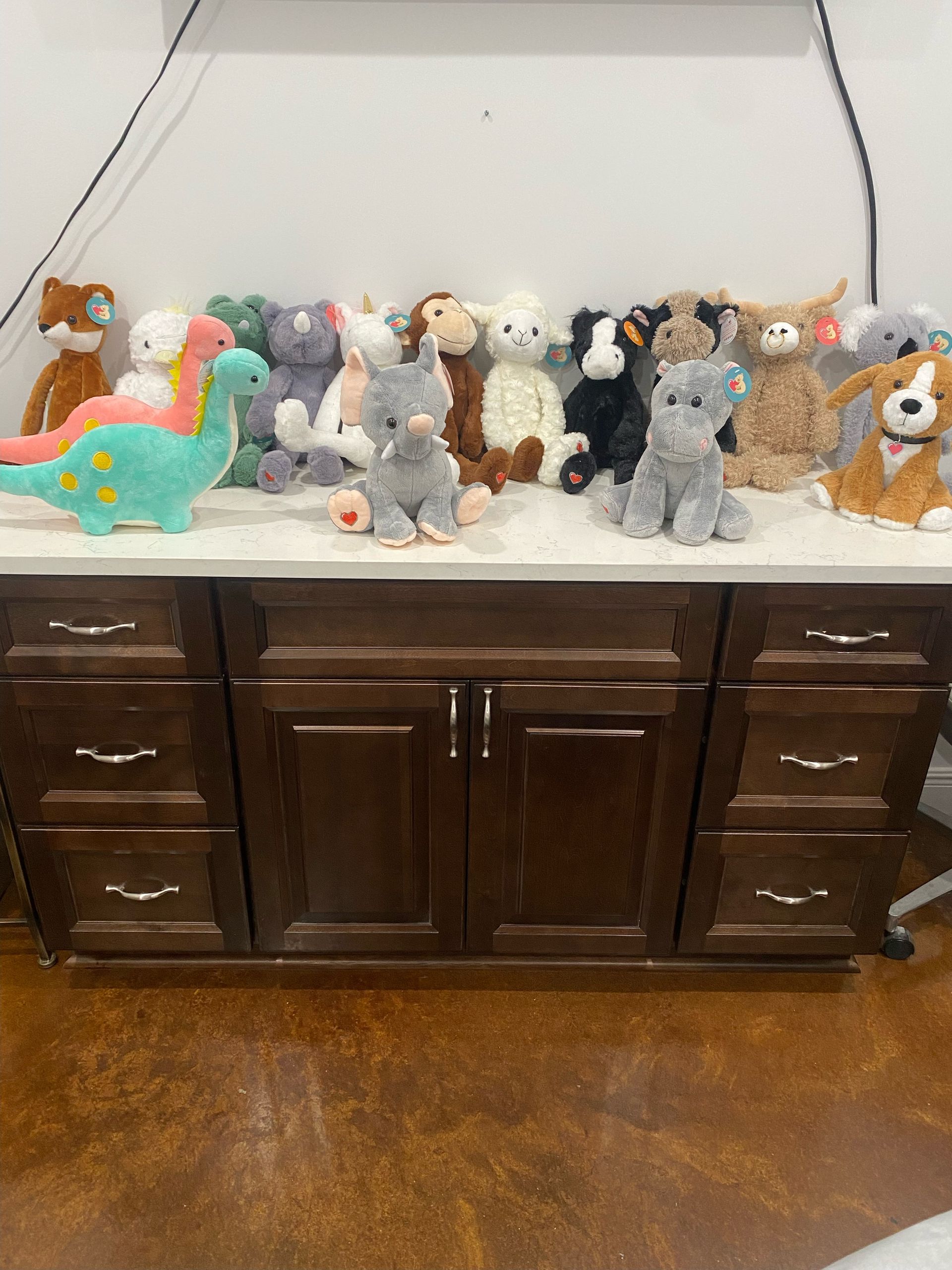 A bunch of stuffed animals are sitting on a counter.