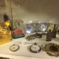 A display case containing antique pocket watches, a vintage banknote, and a golden decorative cat figure.
