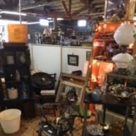 An interior view of a store filled with various antique furniture, decorative items, and assorted household goods.
