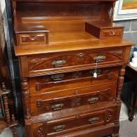 A tall, wooden dresser with a hutch, four large drawers, two small side drawers, and ornate metal handles.