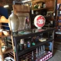 An antique shop display features a red and white Pacific gas station globe atop a glass-topped metal display case.