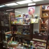 A retail display case filled with various items, including small figurines, snacks, and a 