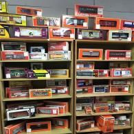 Two shelves filled with numerous boxed model train cars in various colors and designs.