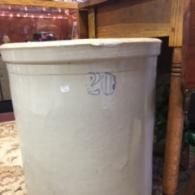 A large, cylindrical, off-white ceramic crock with a blue number 