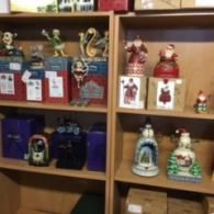 Two wooden shelves displaying assorted Christmas figurines and their corresponding product boxes.