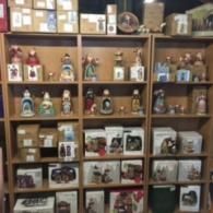 A multi-tiered wooden shelving unit filled with boxed and unboxed collectible figurines, ornaments, and decor items.