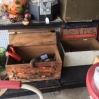 A wooden crate containing tools sits on a shelf next to an open 
