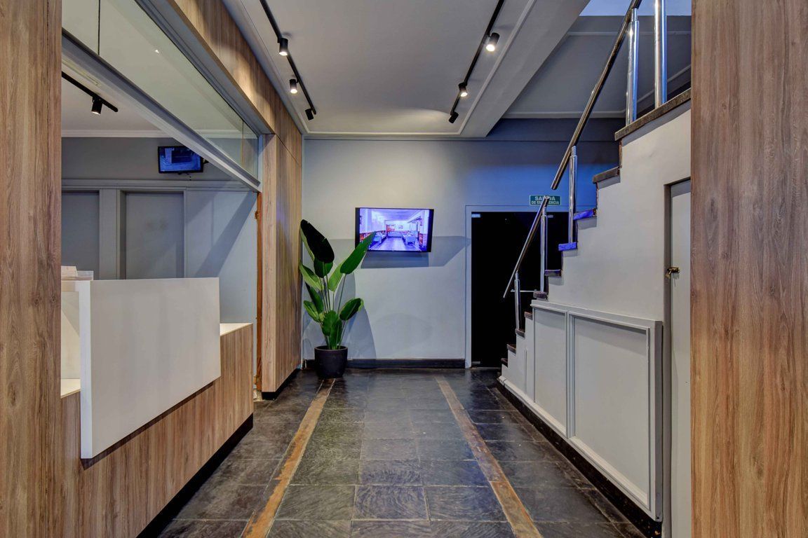 Un largo pasillo con escaleras y un televisor en la pared.