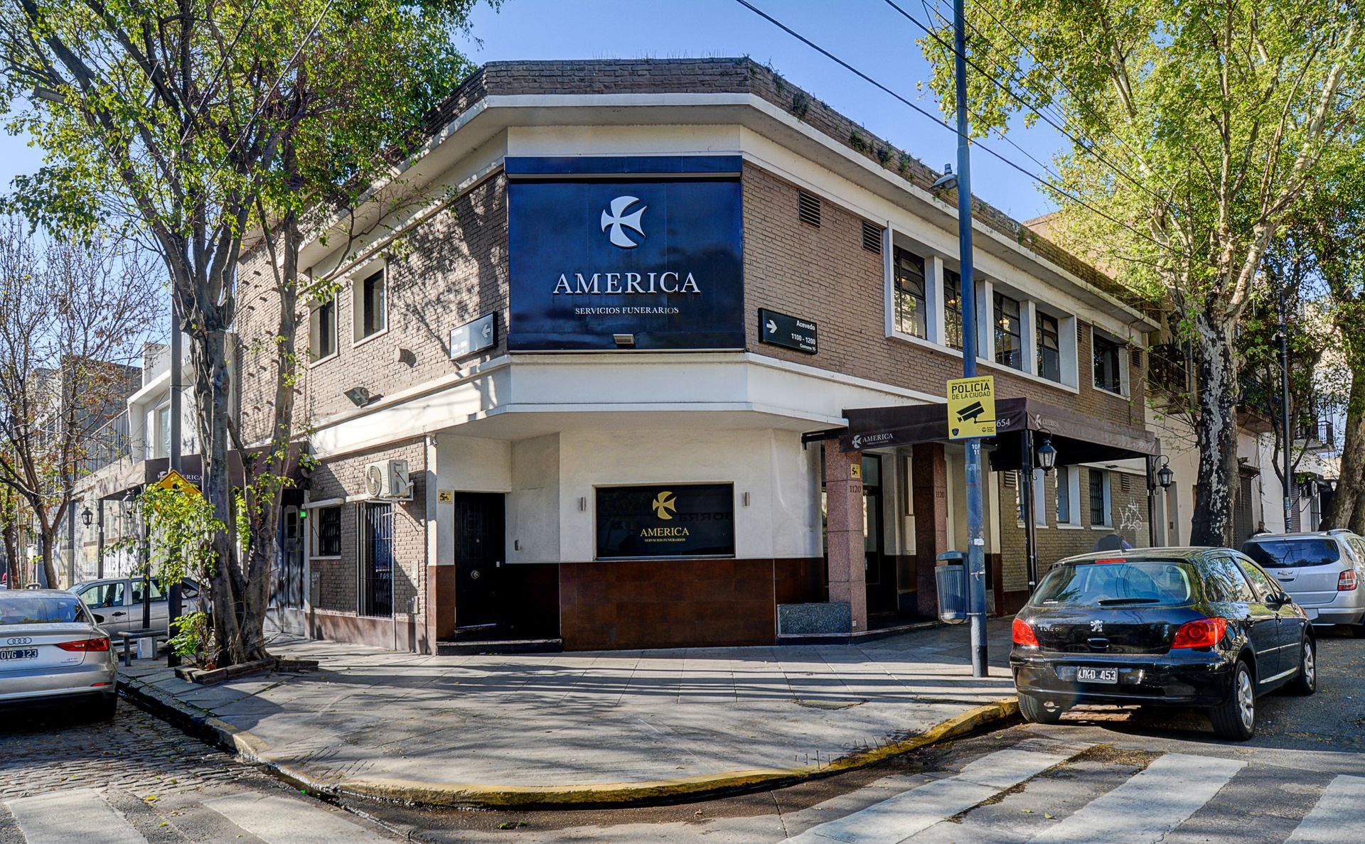 Un edificio en la esquina de una calle con coches aparcados delante de él.