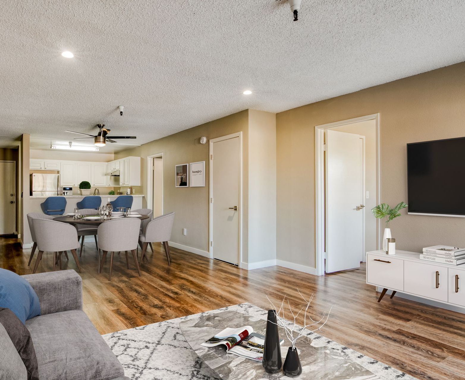 A living room with a couch , table , chairs and a flat screen tv.