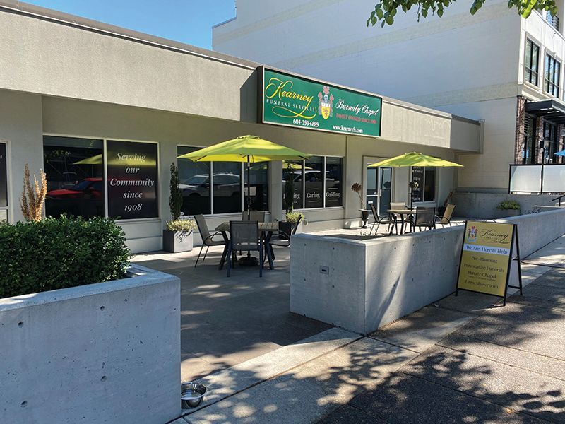 The exterior of Harmony Beauty Salon with lime green umbrellas over patio tables on a sunny day.