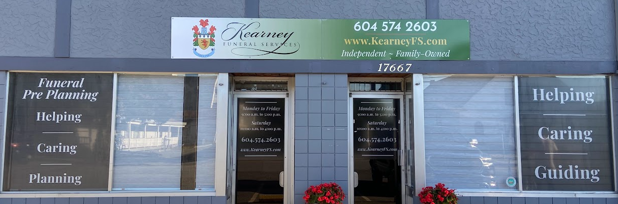 A storefront for a funeral home with a green sign and windows displaying text like 