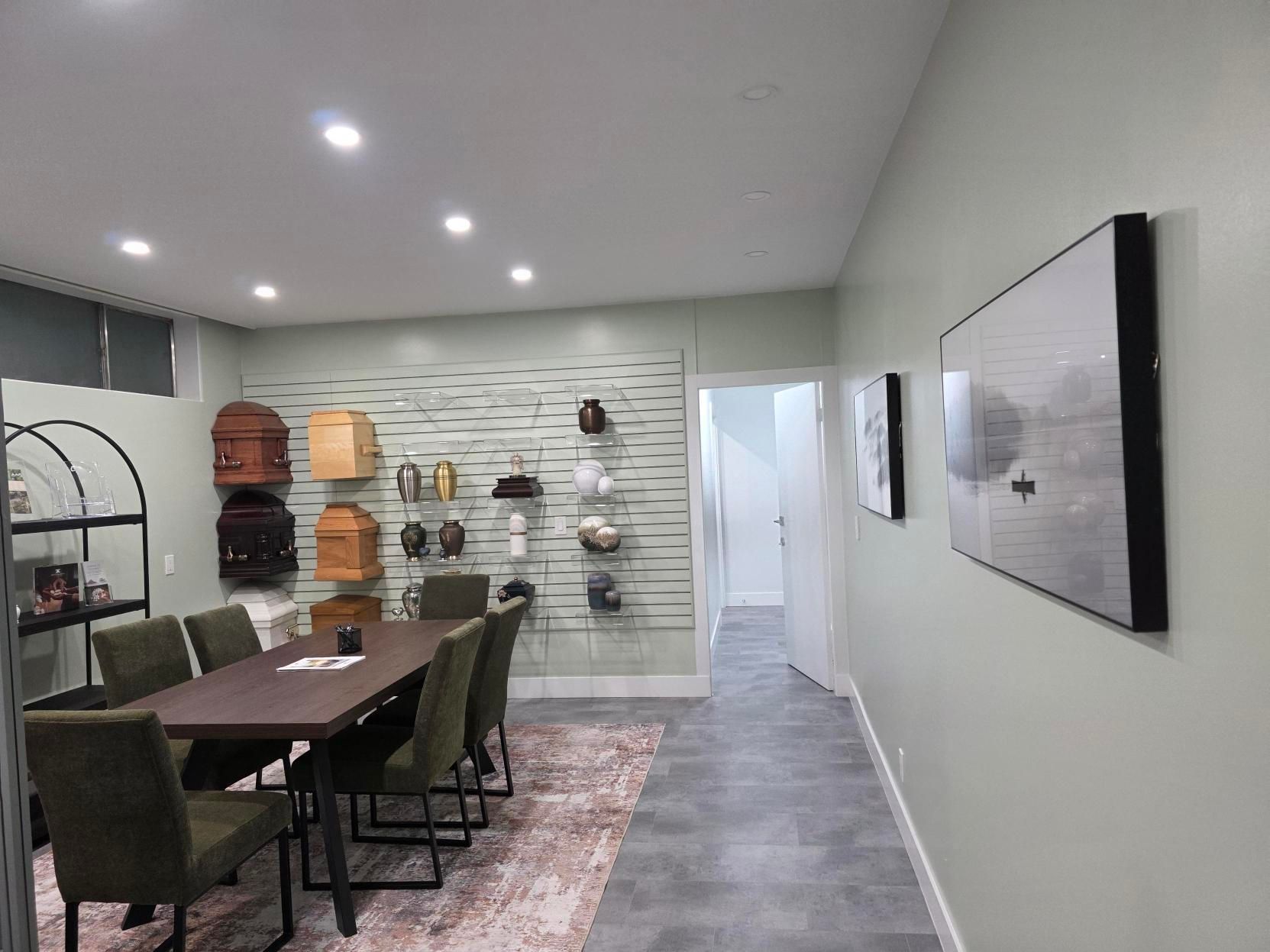 A room with a conference table, chairs, and wall-mounted cremation urn displays, suggesting a funeral arrangement office.