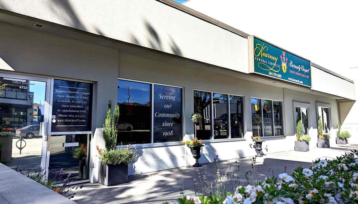 Exterior view of a commercial storefront with a tan facade, large windows, and signage for 