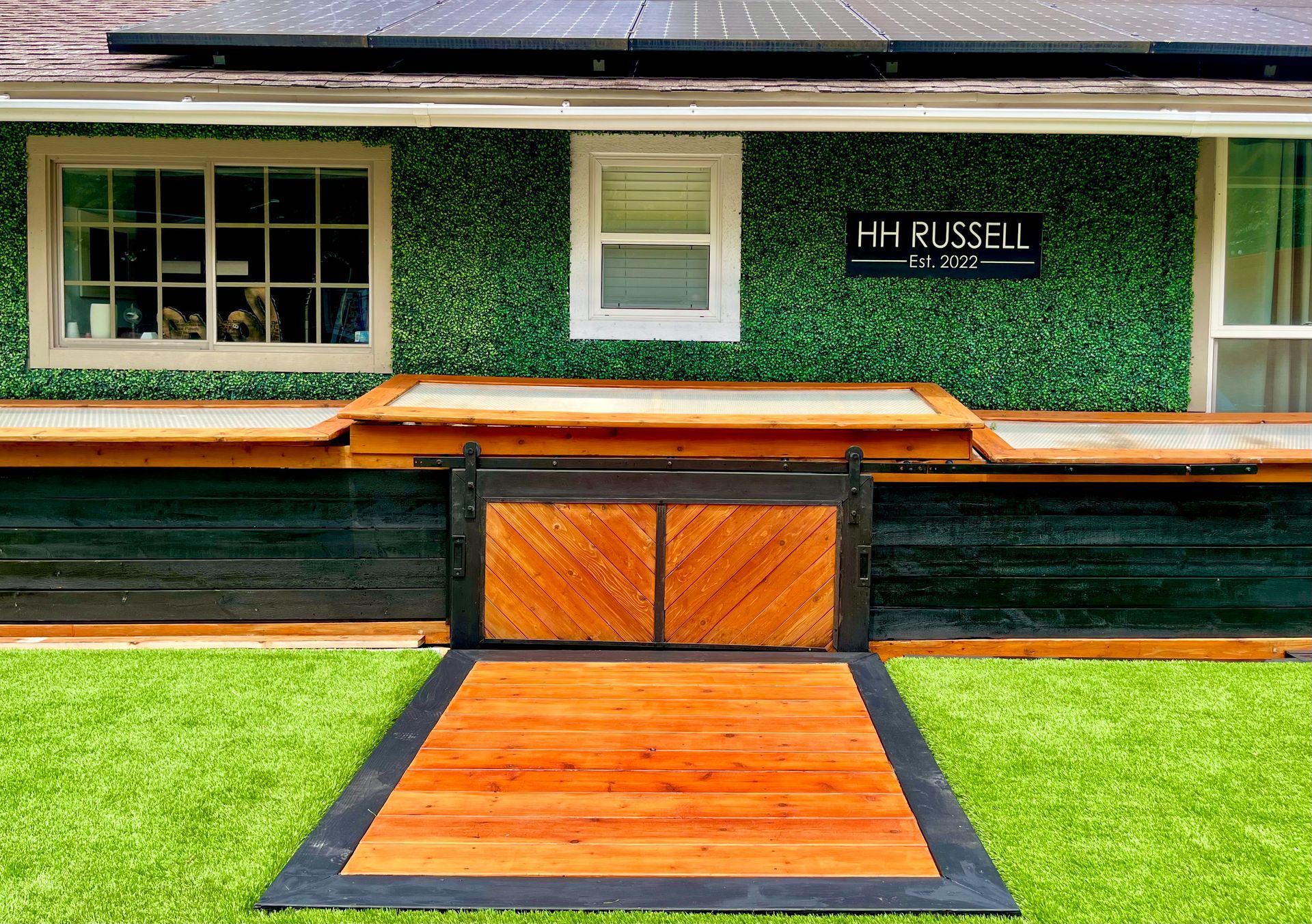 Exterior of a green ivy-covered building with an orange ramp and black trim leading to the entrance
