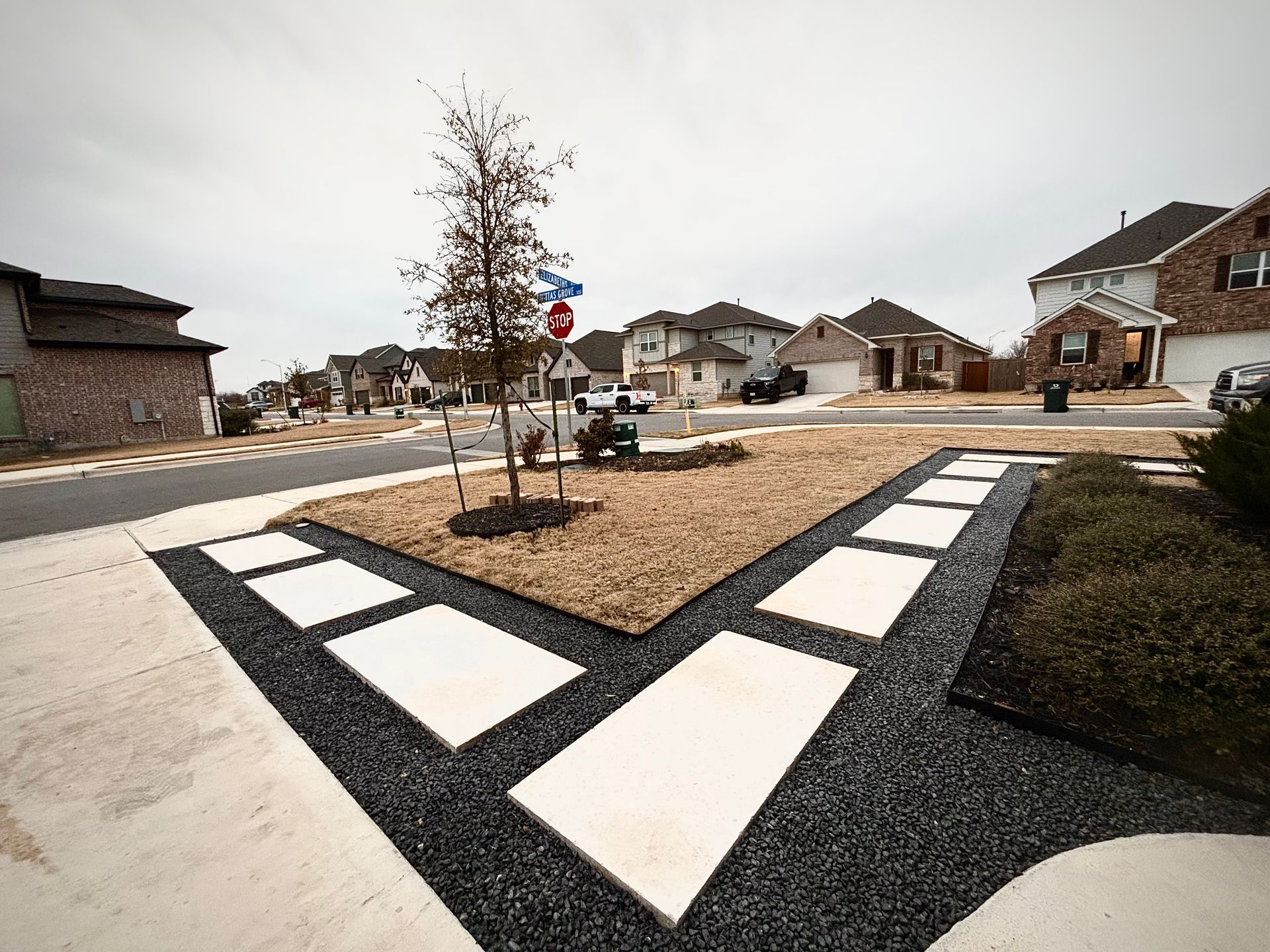 Residential street corner with a landscaped traffic island and black-and-white patterned curb markings