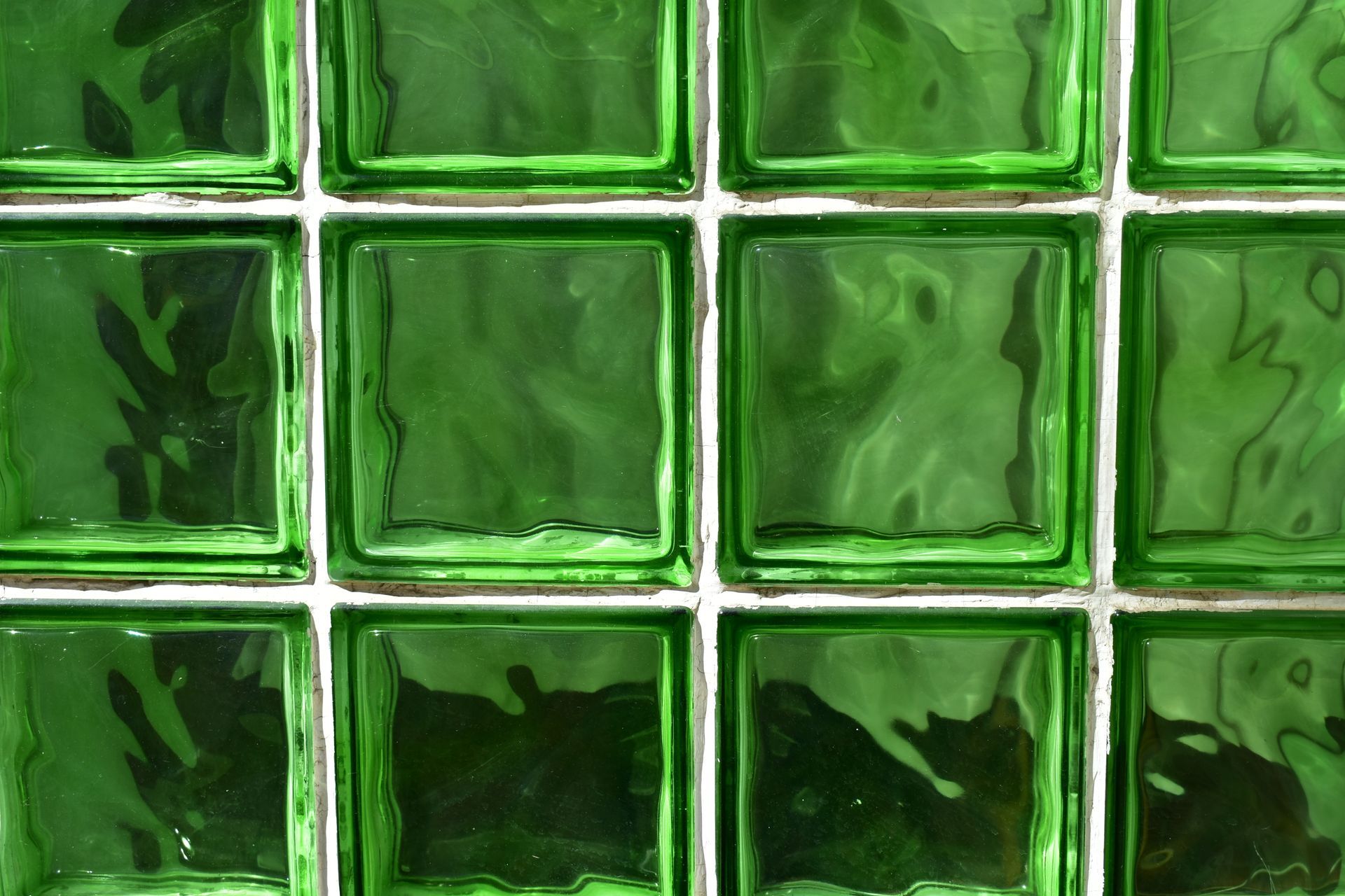 A grid of square, green-tinted textured glass blocks set within white mortar joints.