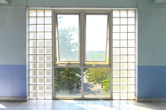 A central window with two glass panes flanked by vertical panels of square glass blocks in a room with blue walls.