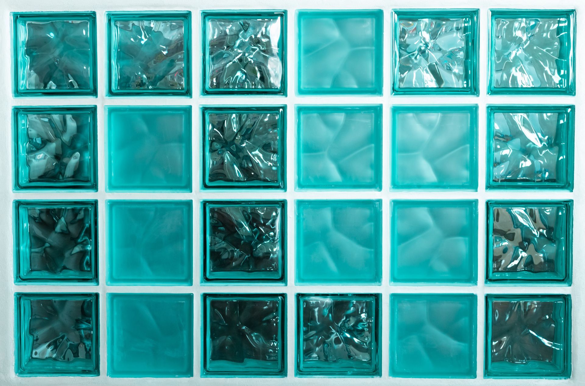 A grid of teal glass blocks, showing a mix of smooth and textured surfaces.