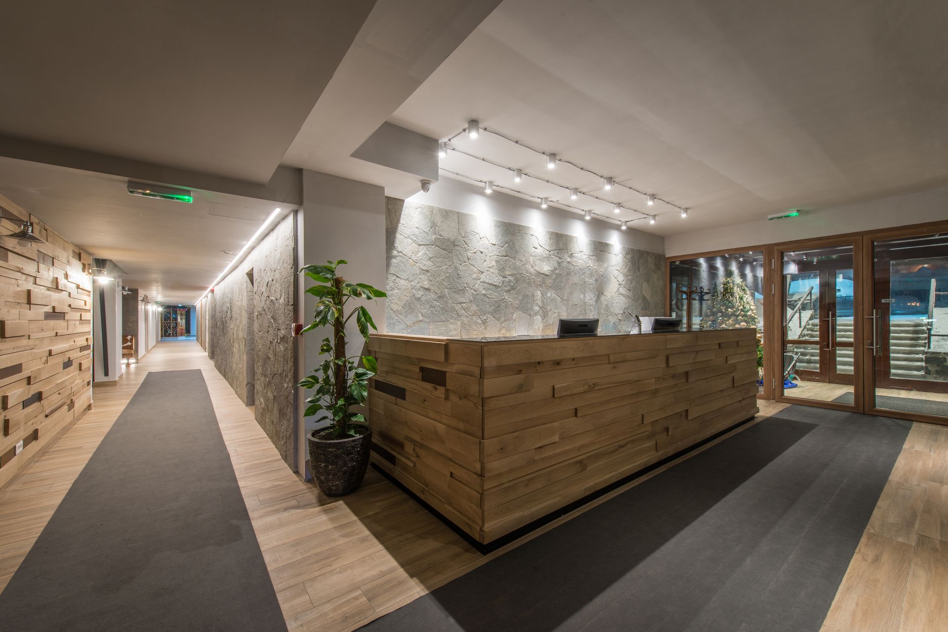 Modern office lobby with wood reception desk, stone walls, and carpeted hallway