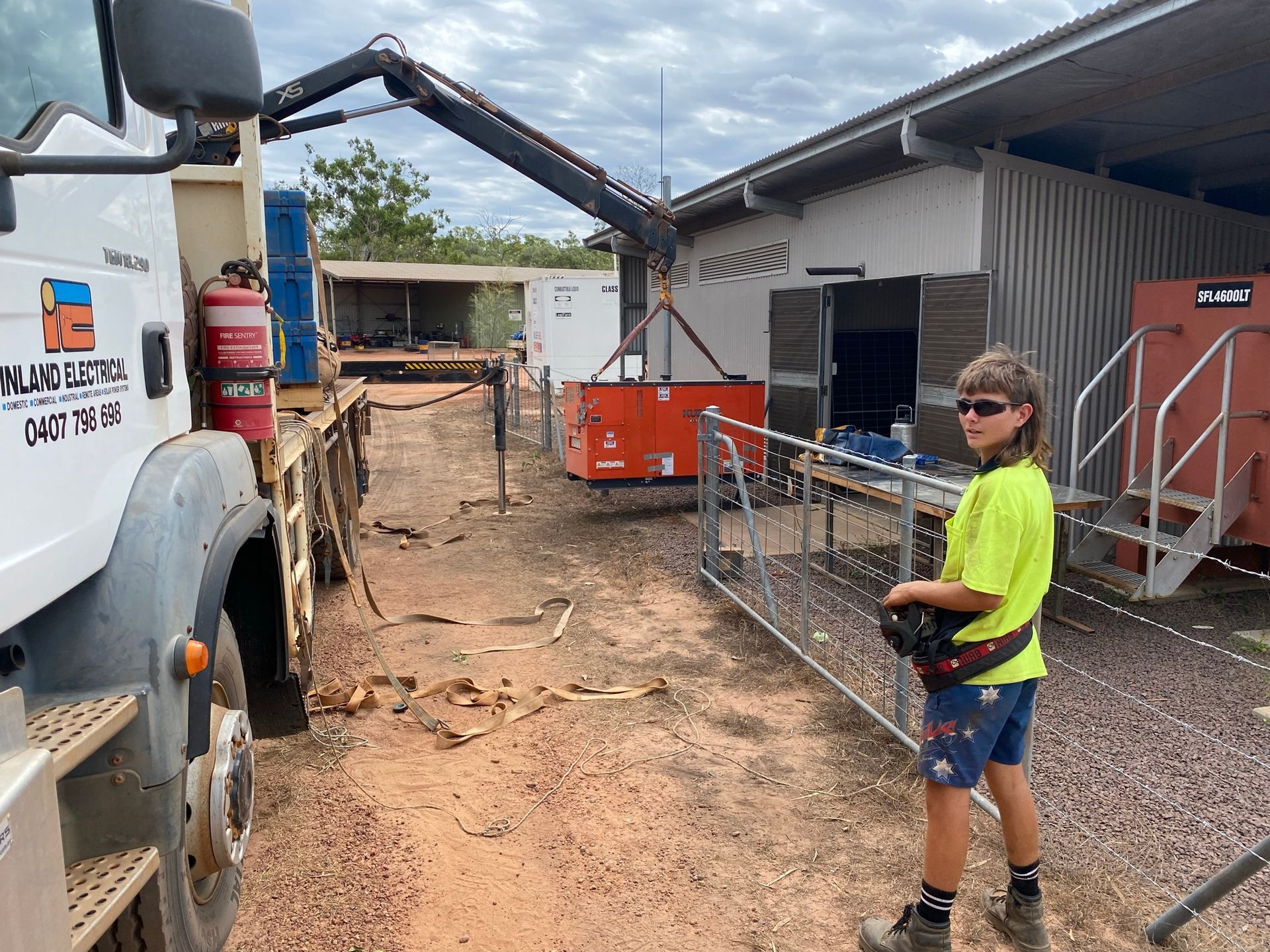 A Boy Next To A Crane Placing A large Orange Box — Inland Electrical in Humpty Doo, NT