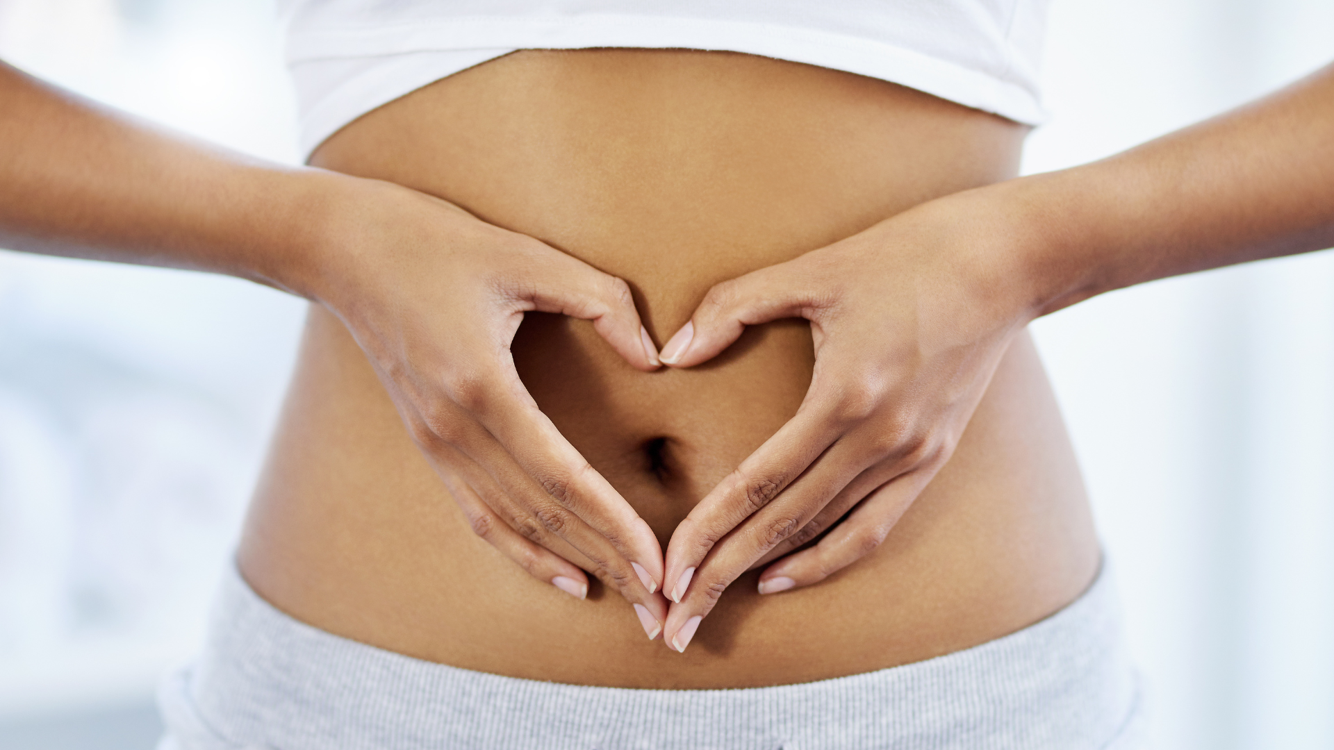 Person giving a pregnant woman an ultrasound scan.  The woman lies on a table in a medical setting.