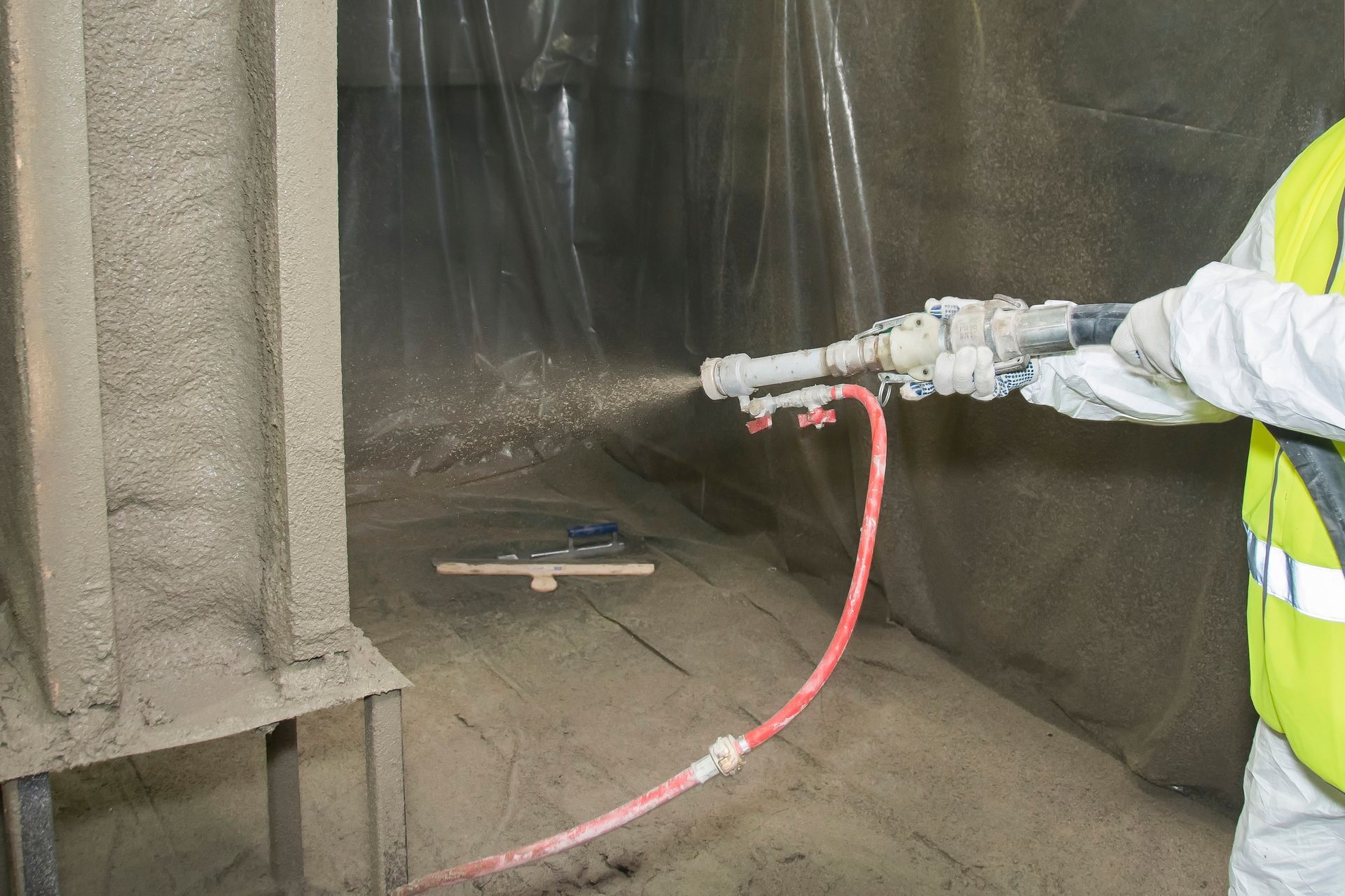 A man is spraying a wall with a hose.