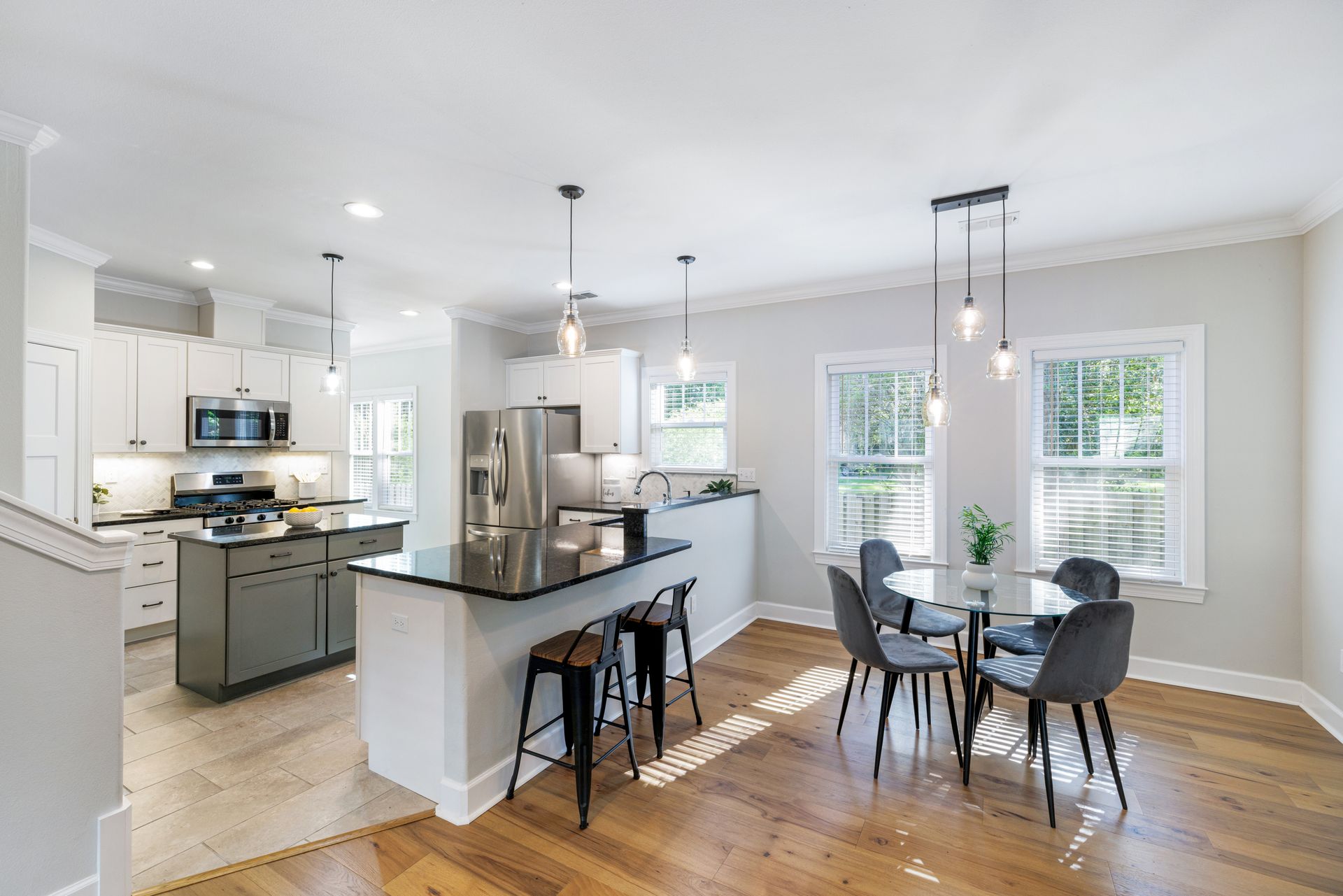 Modern kitchen and dining area with hardwood floors, a breakfast bar, and a round dining table.