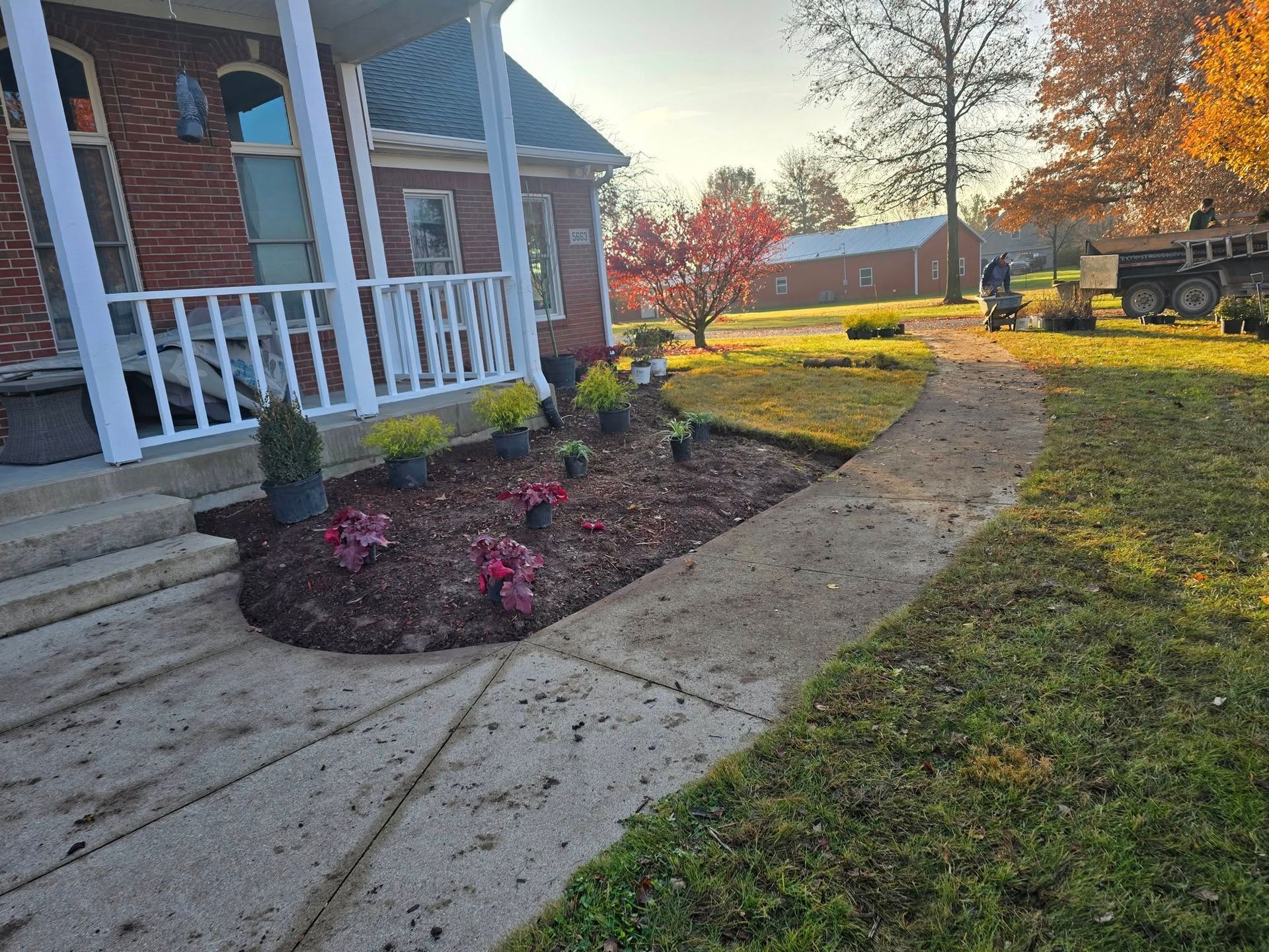 Brick house with new flower bed, sidewalk, and landscaping in yard.