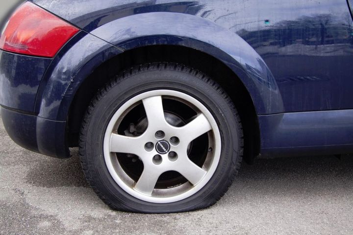 A flat tire on the roadside in need of repair